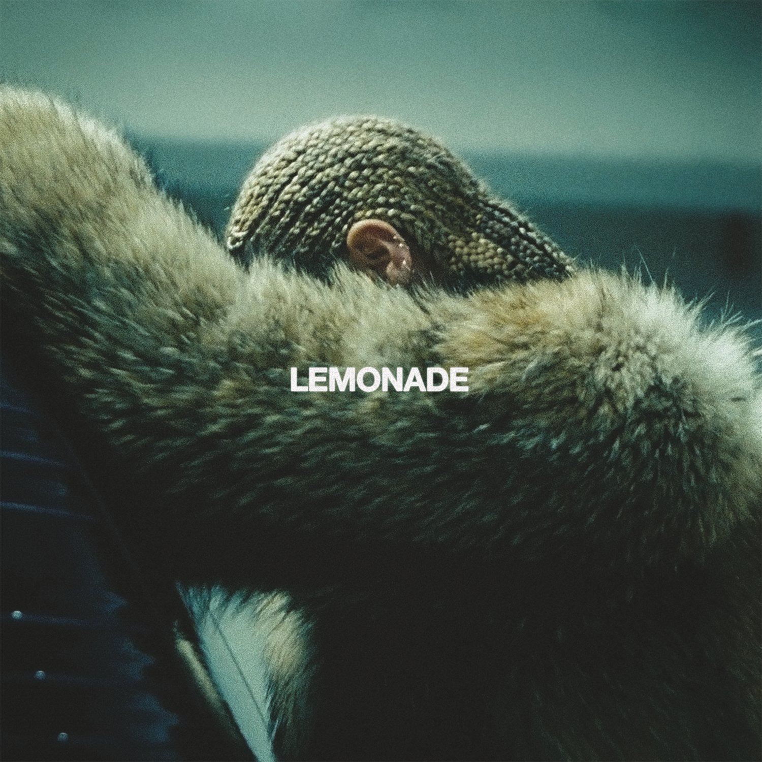 Cover de l'album Lemonade de Beyonc&eacute;. Elle est photographi&eacute;e de profil, face &agrave; une voiture, appuy&eacute;e sur elle. Son bras cache son visage. Elle est coiff&eacute;e de tresse cornrows et porte un manteau de fourrure. Le ton de la photo est vert.