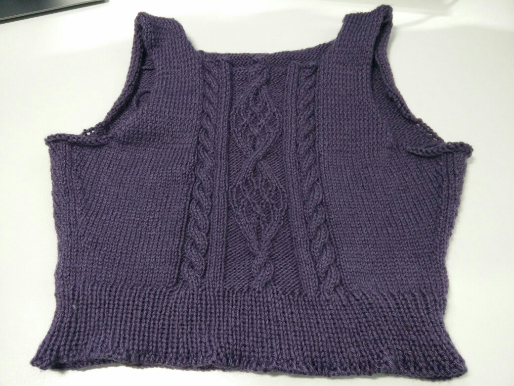 Photo d'un pull en cours de tricot, avec une grosse torsade triple au milieu du torse