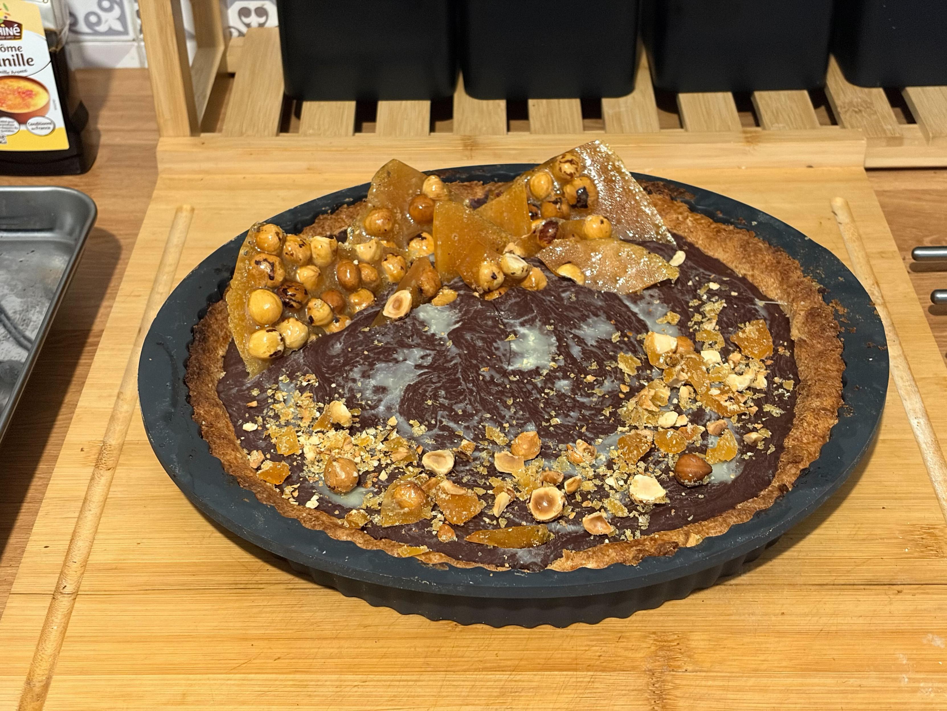 photo d'une tarte au chocolat, avec des morceaux de pralin&eacute; (sucre caram&eacute;lis&eacute; + noisettes) plant&eacute;s dedans