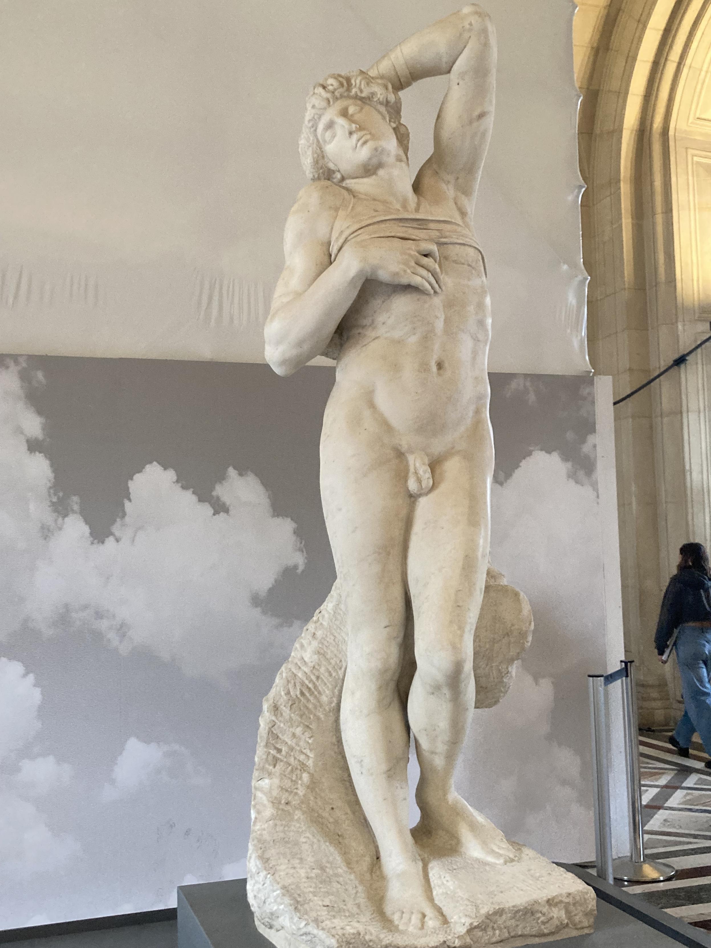 Statue d’un homme debout, nu, une main sur sa poitrine et une main sur sa tête, la tête penchée en arrière d’un air dramatique