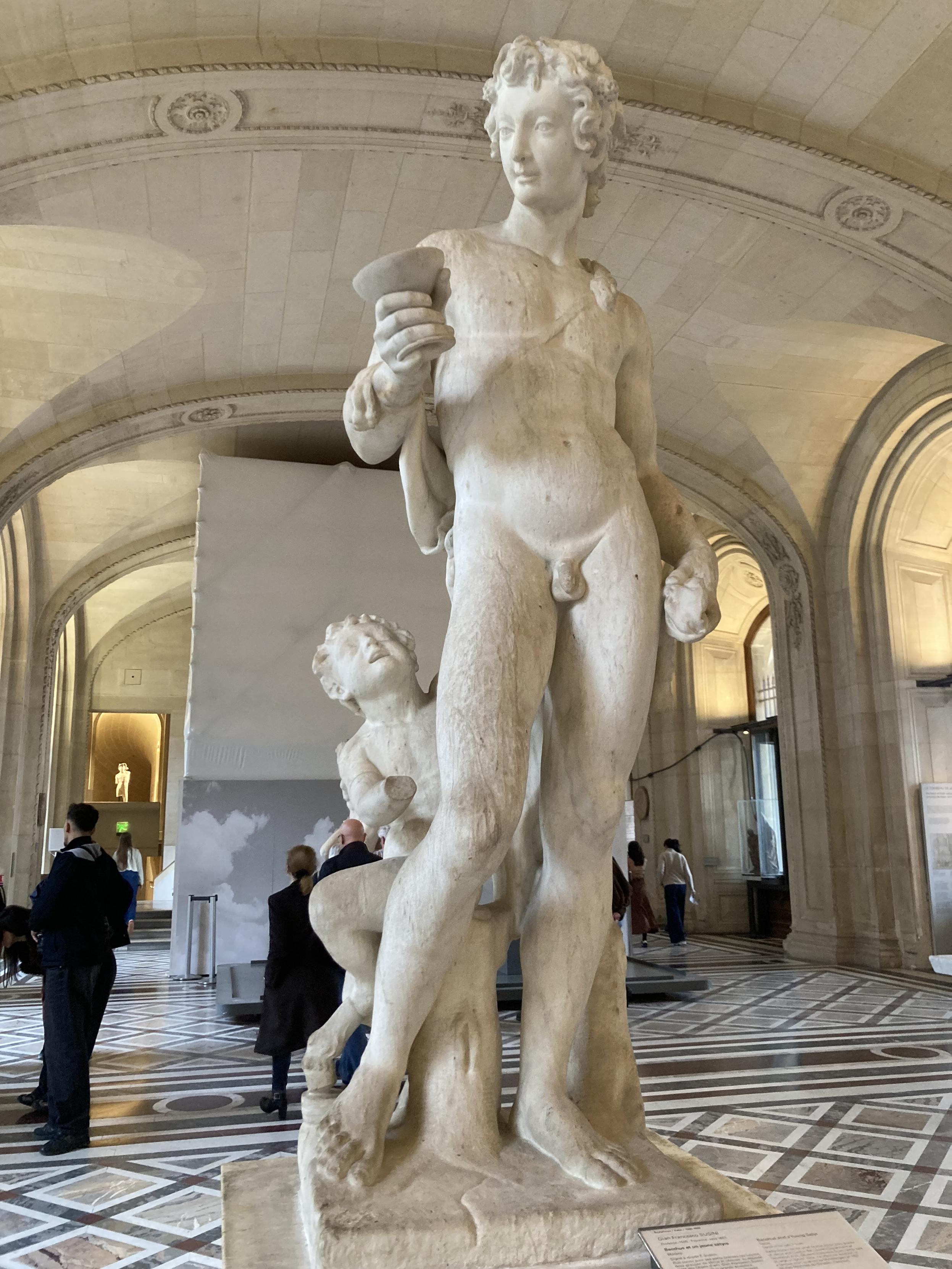 Statue d’un homme tenant une coupe et visiblement ennuyé par l’enfant qui lui tire la jambe pour attirer son attention