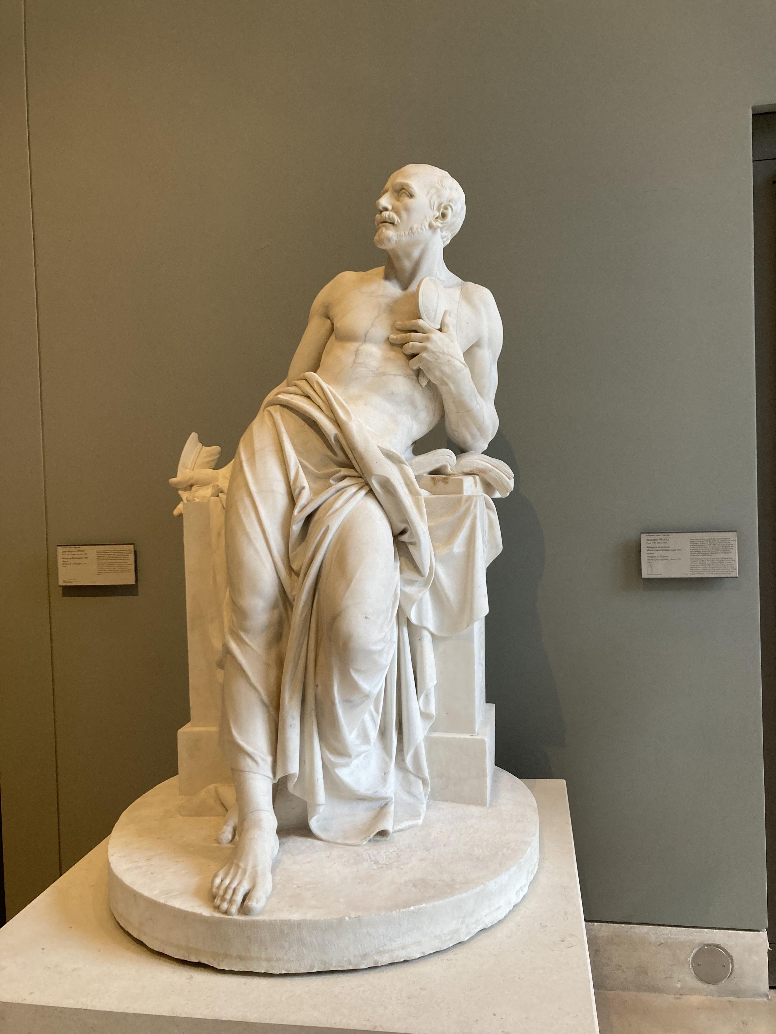 Statue d’un homme torse nu, le bas du corps caché par un drap, dans une pose absolument pas naturelle