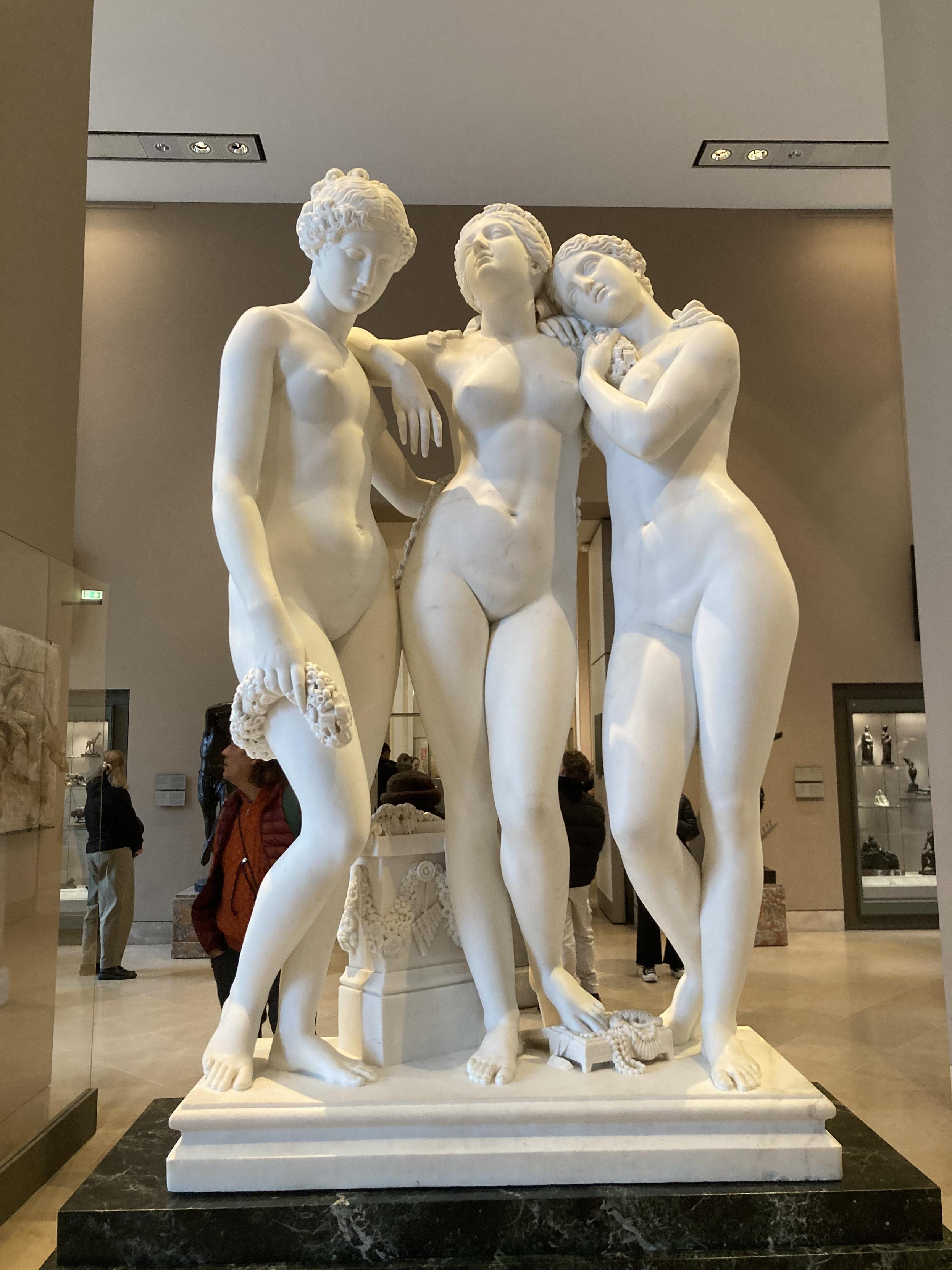 Sculpture de 3 jeunes femmes nues, bras dessus-dessous