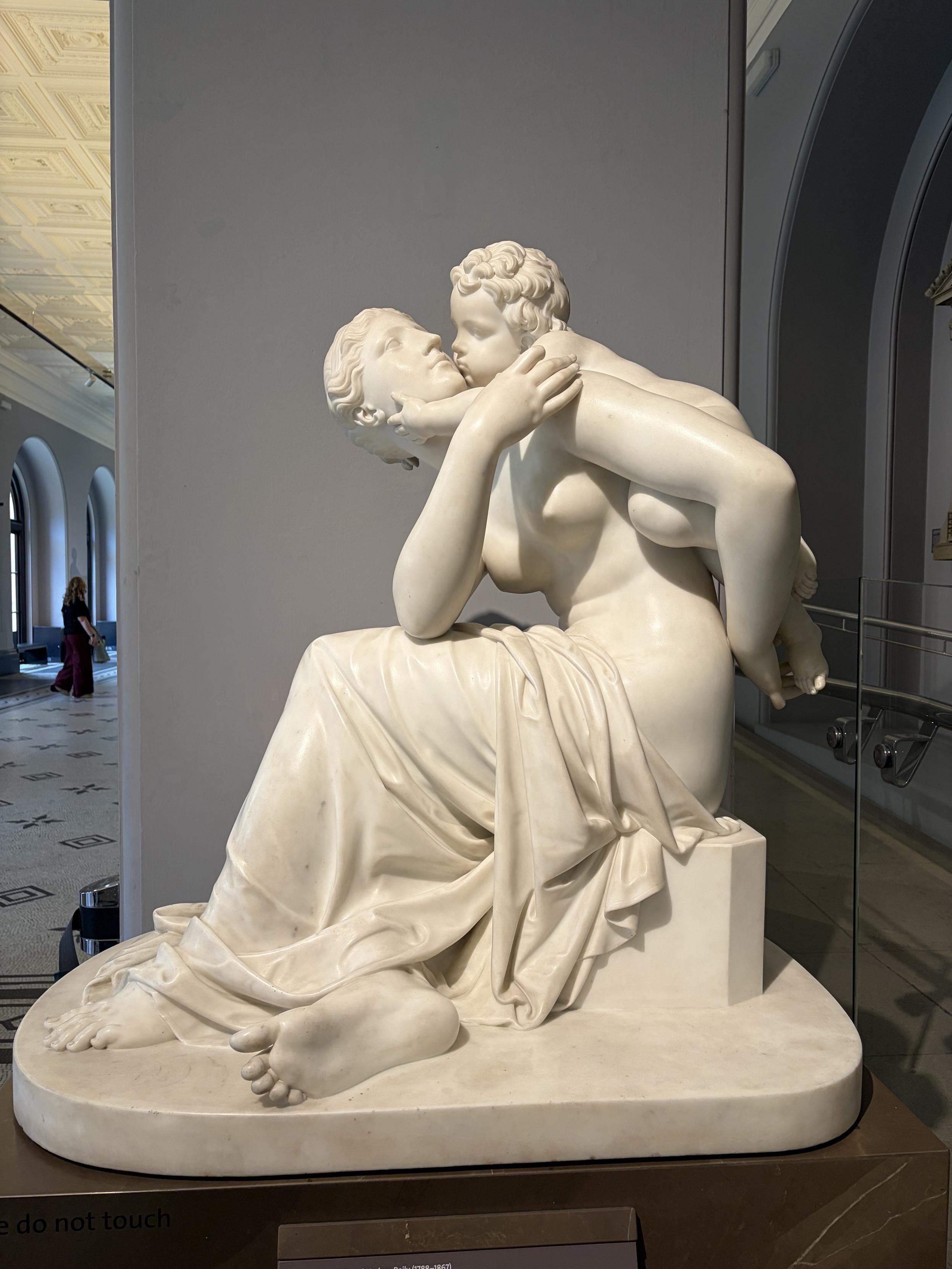 Sculpture d&rsquo;une femme avec son enfant sur le dos, en train de l&rsquo;embrasser